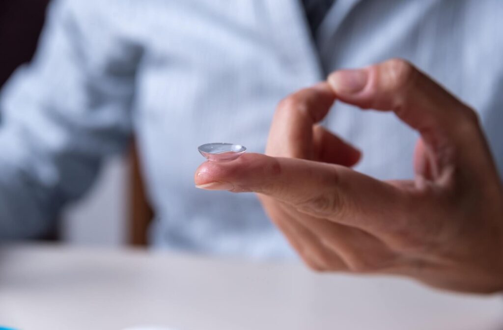 A close-up of a clear daily disposable contact lens balanced on a person's index finger, ready to be inserted into the eye.